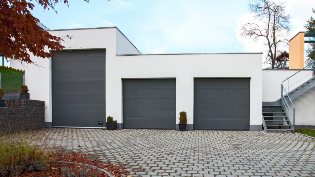Modernes Einfamilienhaus in Chemnitz mit integrierter Dreifachgarage, Flachdach und minimalistisch weißer Fassadengestaltung.